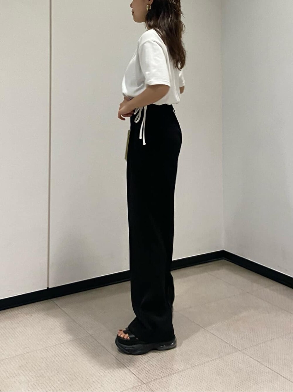 ブラック系のスラックス、ホワイト系のTシャツ/カットソー、イエロー系のショルダーバッグを着用したレディースの春コーディネートの5枚目の写真