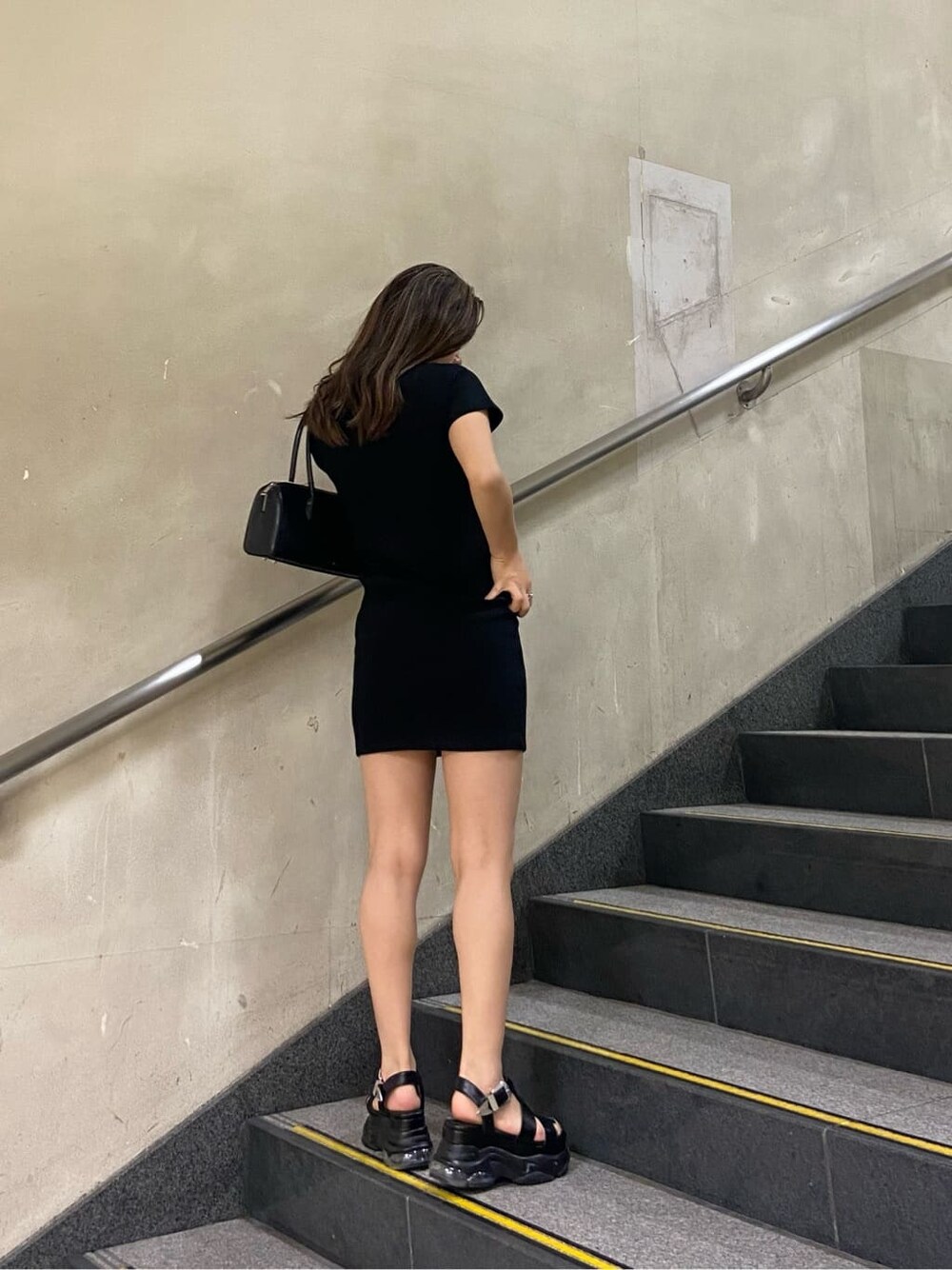 ブラック系のボストンバッグ、ブラック系のワンピース、ブラック系のサンダルを着用したレディースの春コーディネートの5枚目の写真