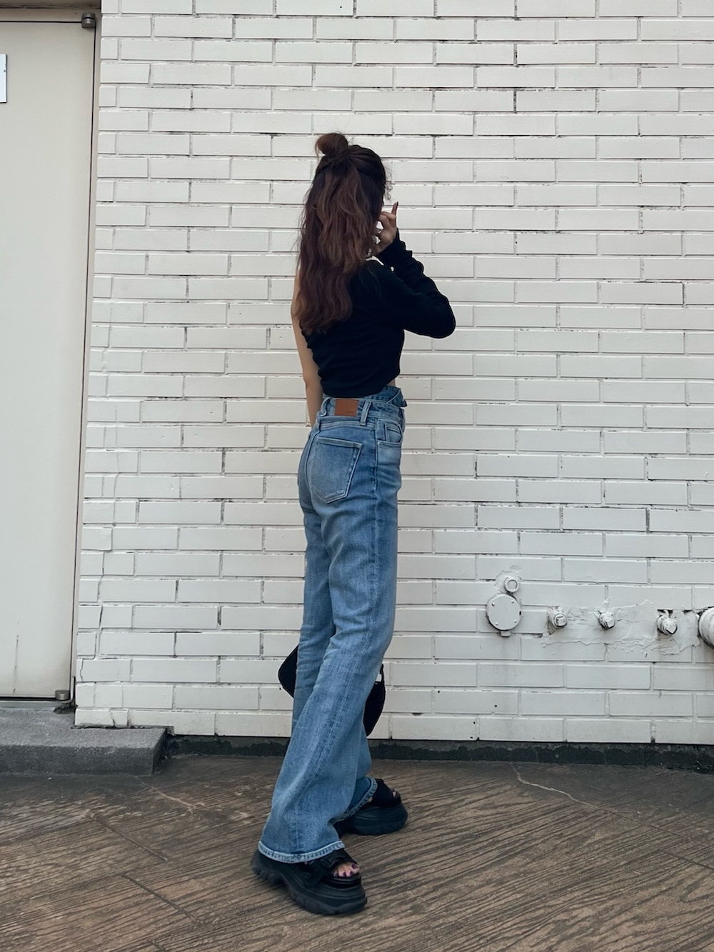 ブラック系のTシャツ/カットソー、ブラック系のサンダル、ブルー系のデニムパンツを着用したレディースの夏コーディネートの4枚目の写真