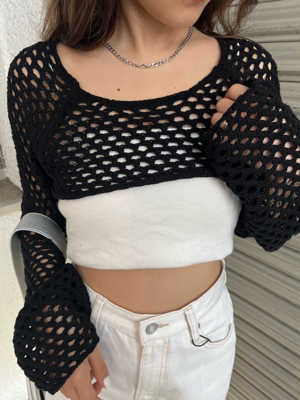 ホワイト系のデニムパンツ、ブラック系のサンダル、ブラック系のニット/セーターを着用したレディースの春コーディネートの6枚目の写真