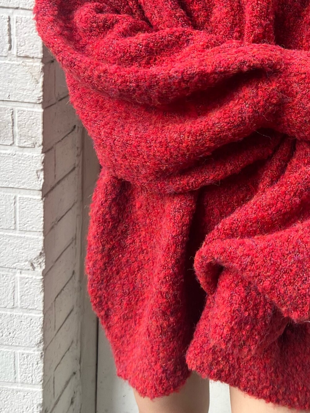 レッド系のニット/セーター、ブラック系のブーツを着用したレディースの冬コーディネートの6枚目の写真