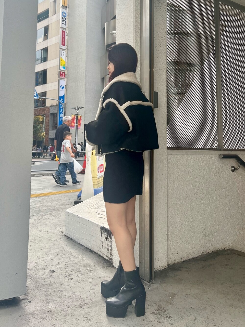 ブラック系のブーツ、ブラック系のムートンコート、ブラック系のワンピースを着用したレディースの秋コーディネートの6枚目の写真