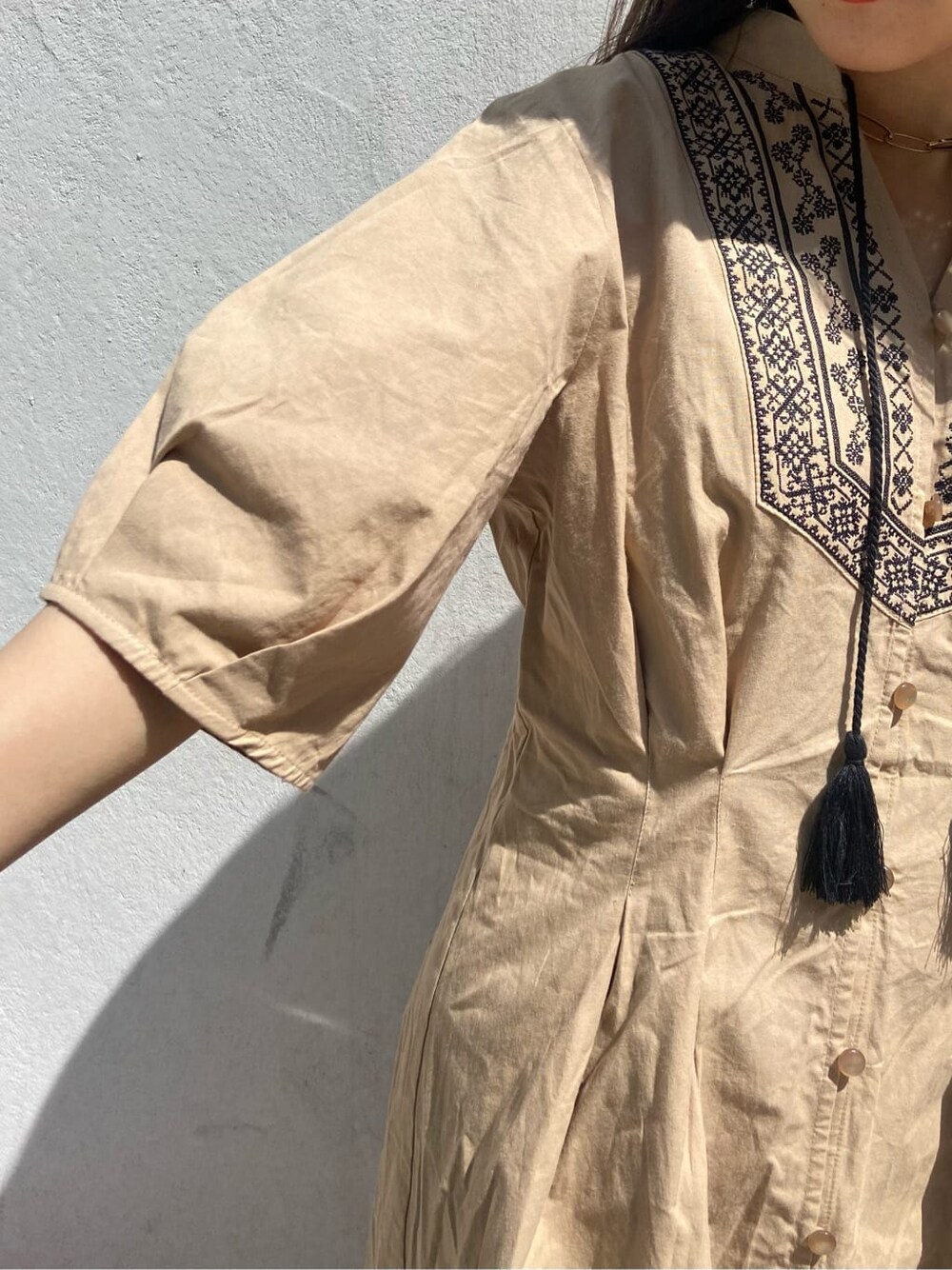 ブラック系のボストンバッグ、ブラック系のブーツ、ベージュ系のワンピースを着用したレディースの春コーディネートの6枚目の写真