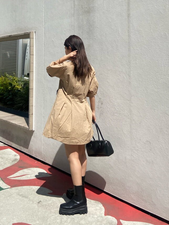 ブラック系のボストンバッグ、ブラック系のブーツ、ベージュ系のワンピースを着用したレディースの春コーディネートの3枚目の写真