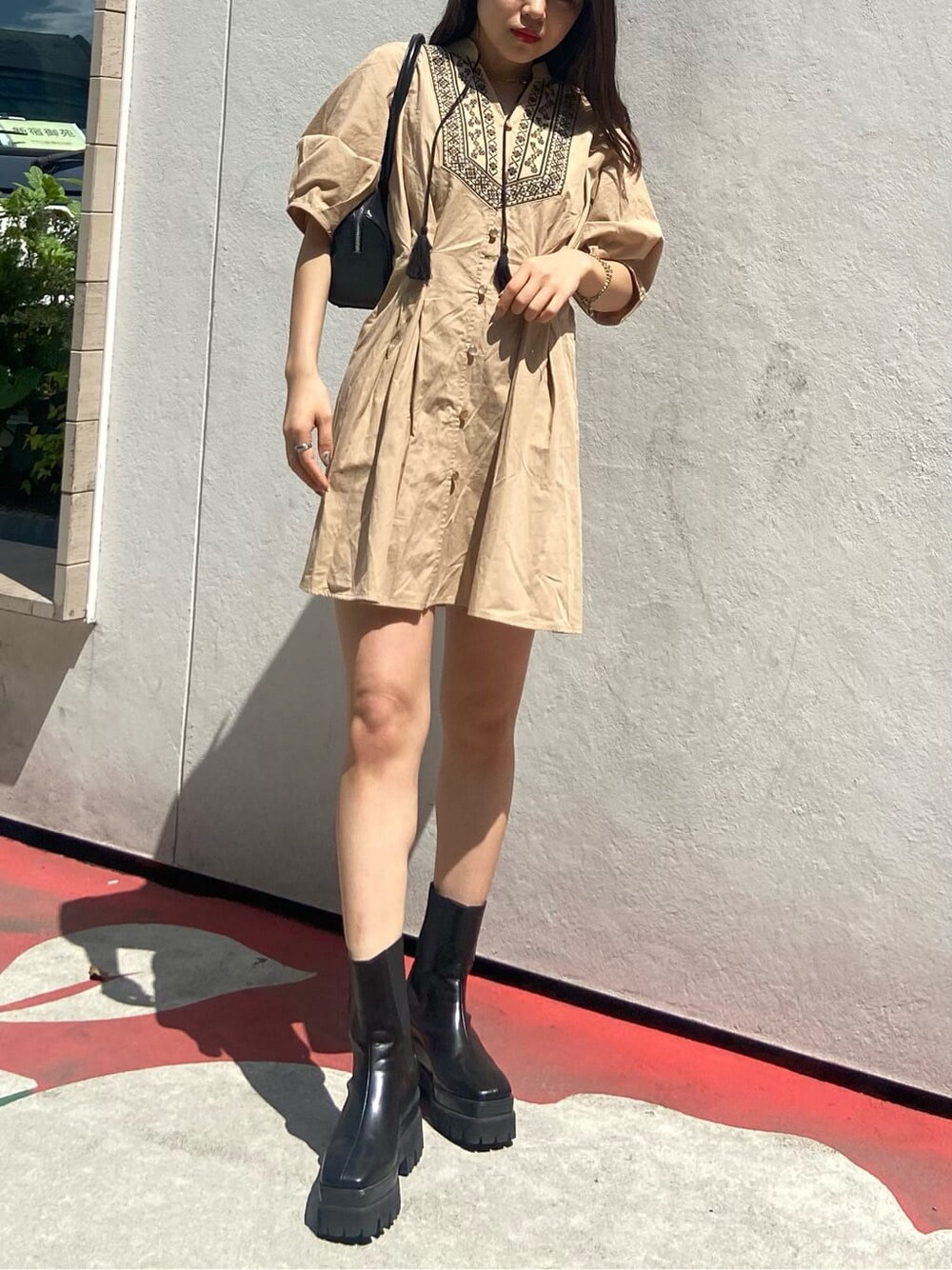 ブラック系のボストンバッグ、ブラック系のブーツ、ベージュ系のワンピースを着用したレディースの春コーディネートの2枚目の写真