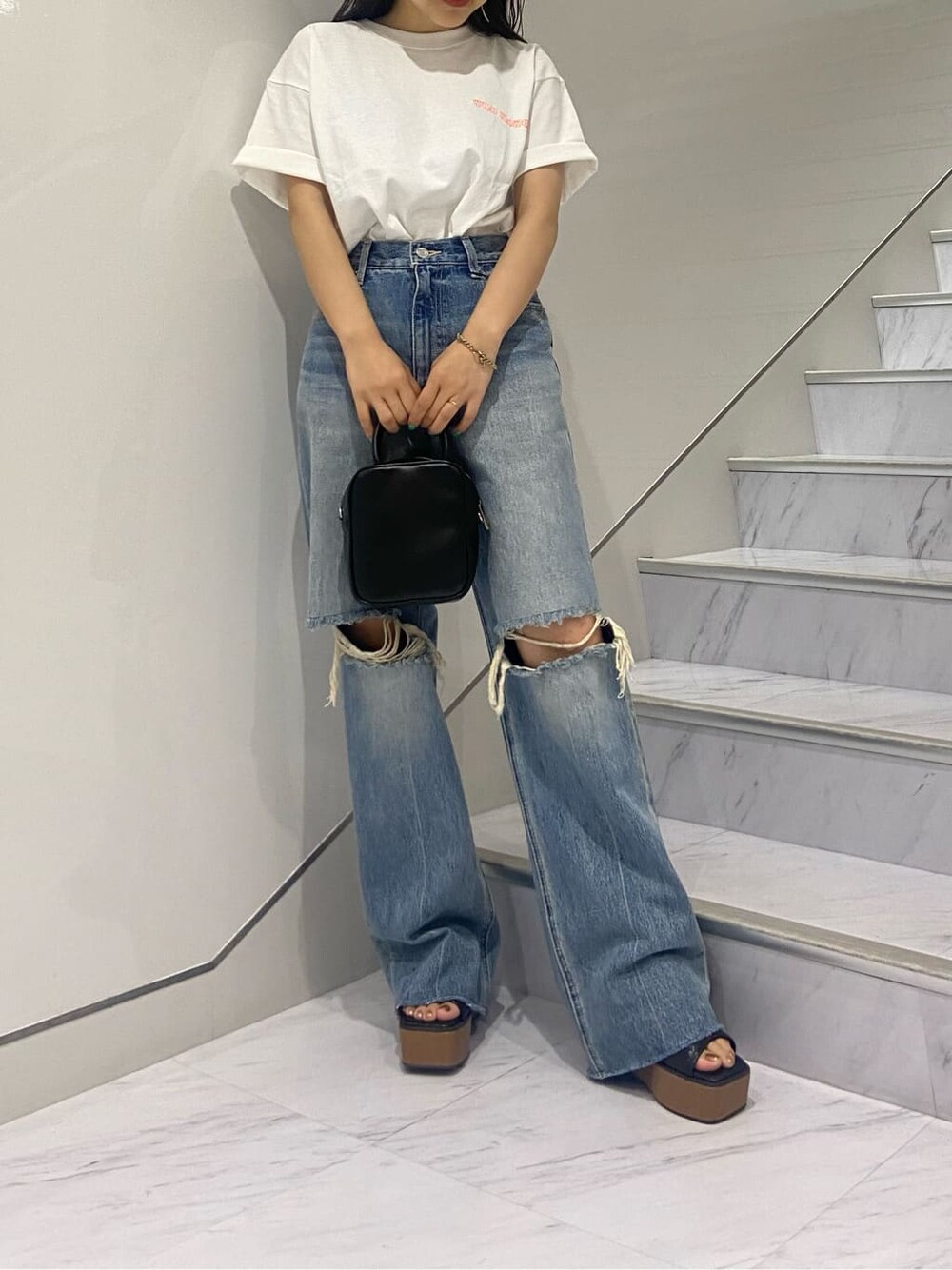 ブラック系のショルダーバッグ、ブラック系のサンダル、ブルー系のデニムパンツを着用したレディースの夏コーディネートの7枚目の写真