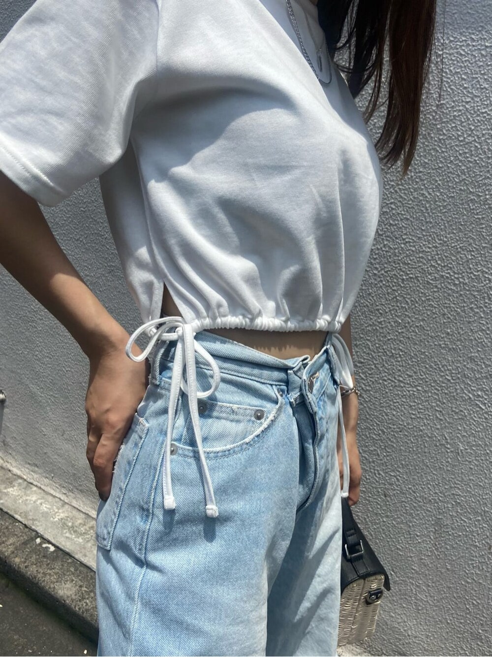 ブラック系のサンダル、ホワイト系のTシャツ/カットソー、ブルー系のデニムパンツを着用したレディースの夏コーディネートの6枚目の写真