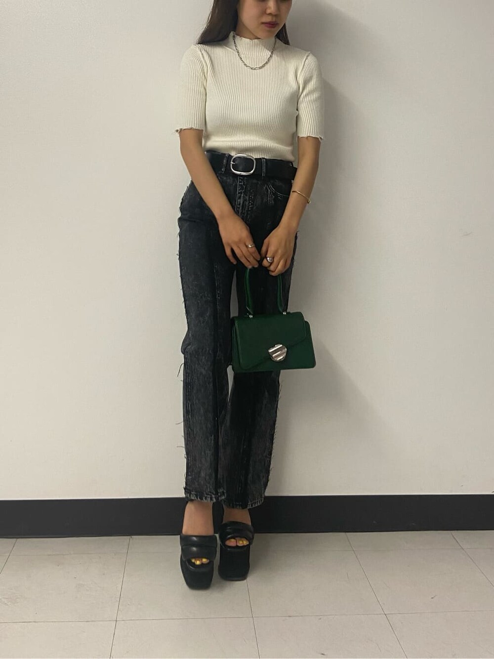 グリーン系のハンドバッグ、ブラック系のデニムパンツ、ホワイト系のニット/セーターを着用したレディースの夏コーディネートの6枚目の写真
