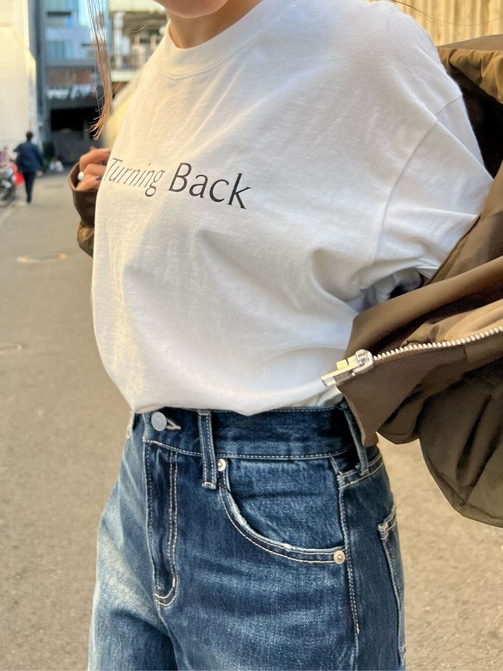 ブラック系のブーツ、ホワイト系のTシャツ/カットソー、ベージュ系のMA-1を着用したレディースの秋コーディネートの5枚目の写真