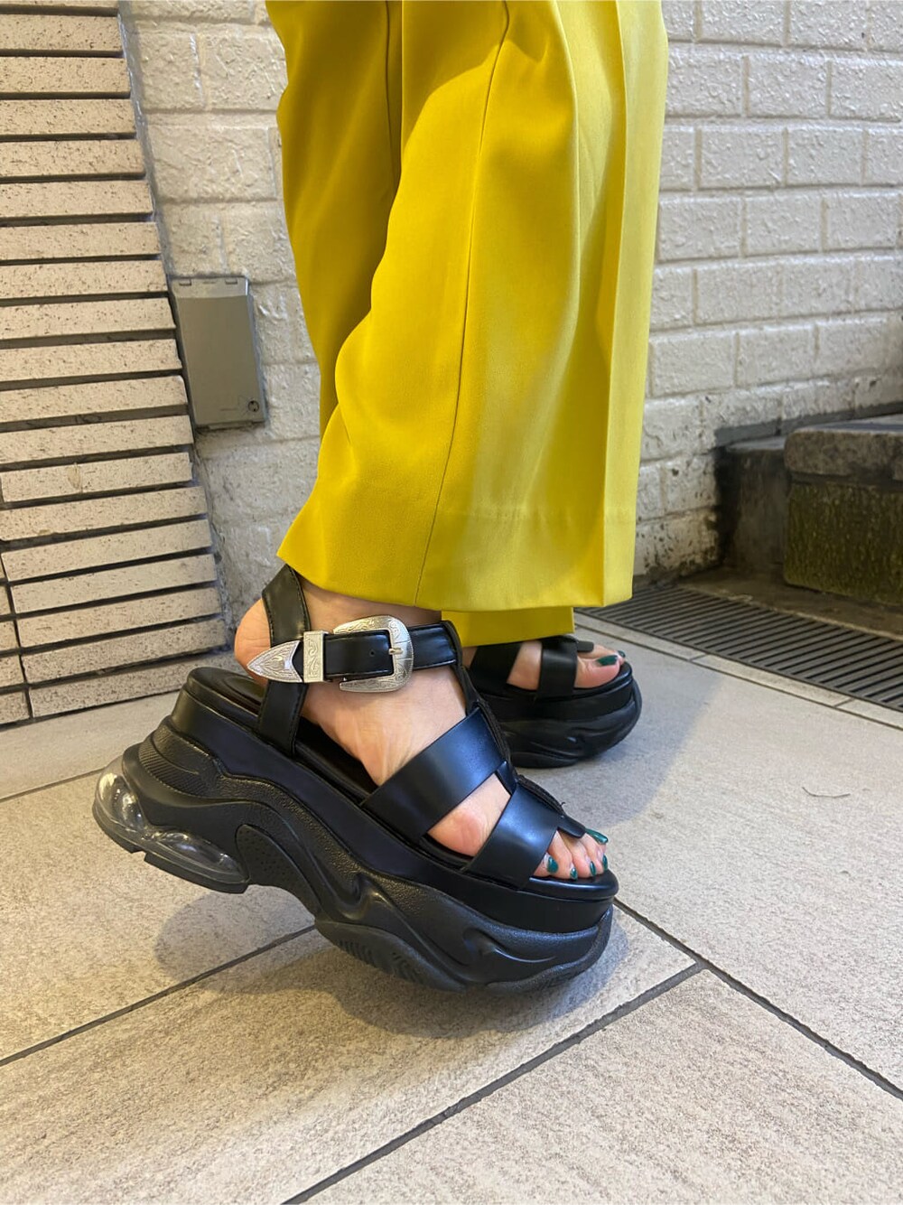 ブラック系のTシャツ/カットソー、グリーン系のデニムパンツ、ブラック系のサンダルを着用したレディースの春コーディネートの7枚目の写真