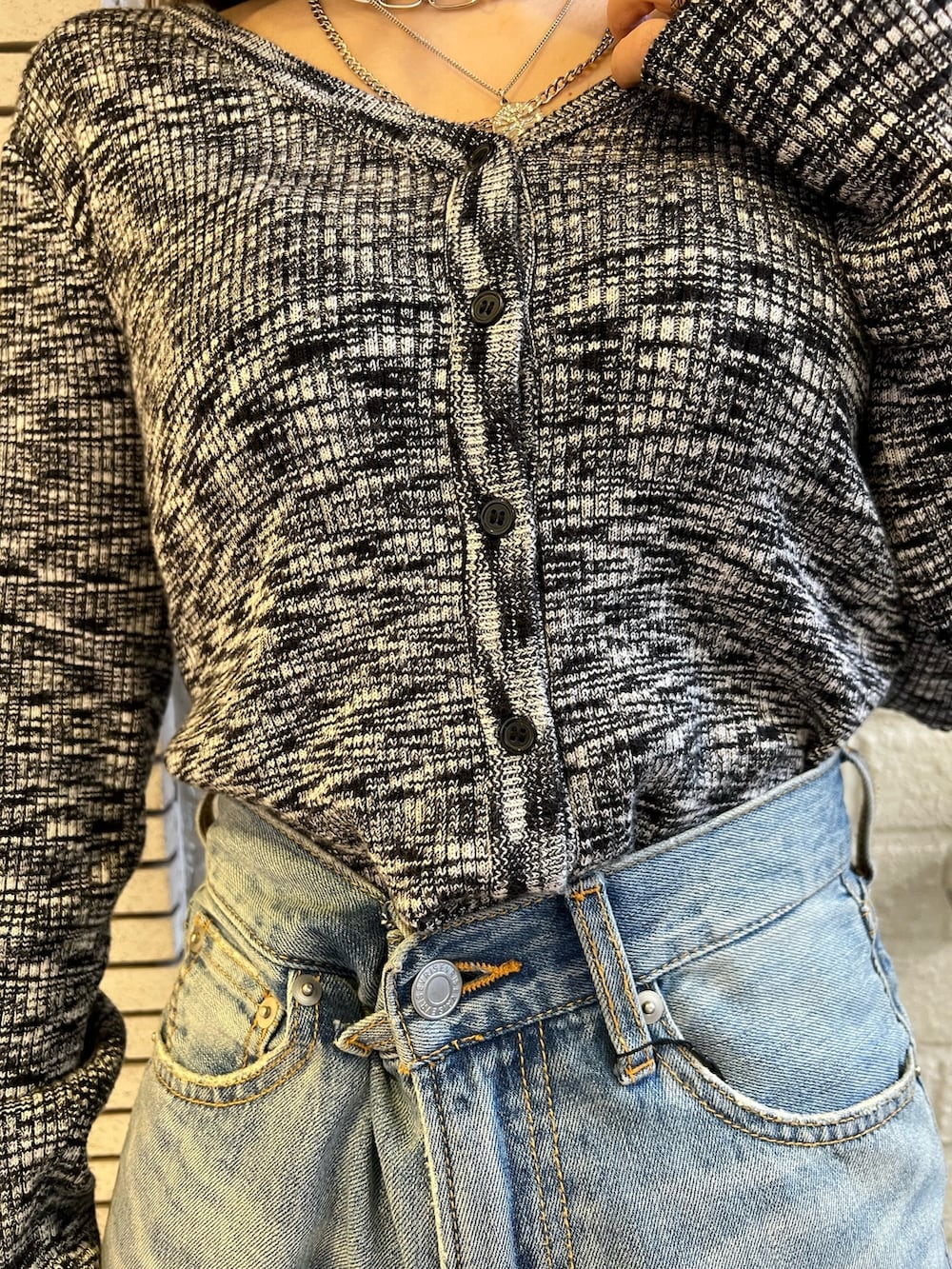 ブルー系のデニムパンツ、ブラック系のハンドバッグ、ブラック系のニット/セーターを着用したレディースの冬コーディネートの6枚目の写真