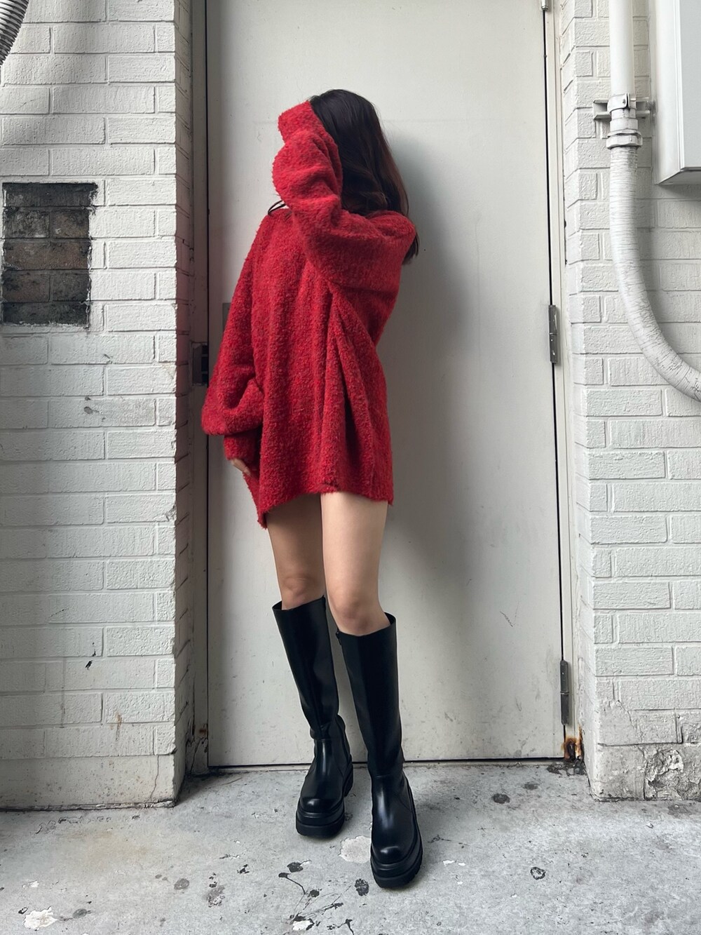 レッド系のニット/セーター、ブラック系のブーツを着用したレディースの冬コーディネートの4枚目の写真