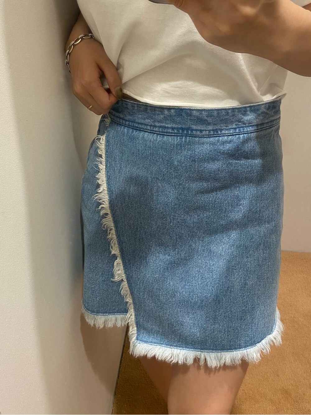 ブルー系のデニムスカート、ホワイト系のTシャツ/カットソー、ホワイト系のサンダルを着用したレディースの夏コーディネートの3枚目の写真