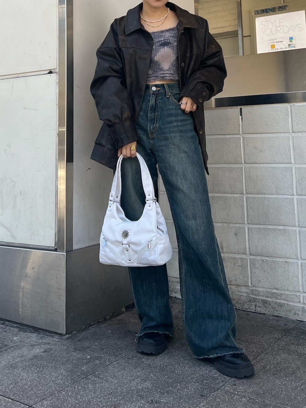 ブルー系のデニムパンツ、ホワイト系のハンドバッグ、ブラック系のブーツを着用したレディースの冬コーディネートの3枚目の写真