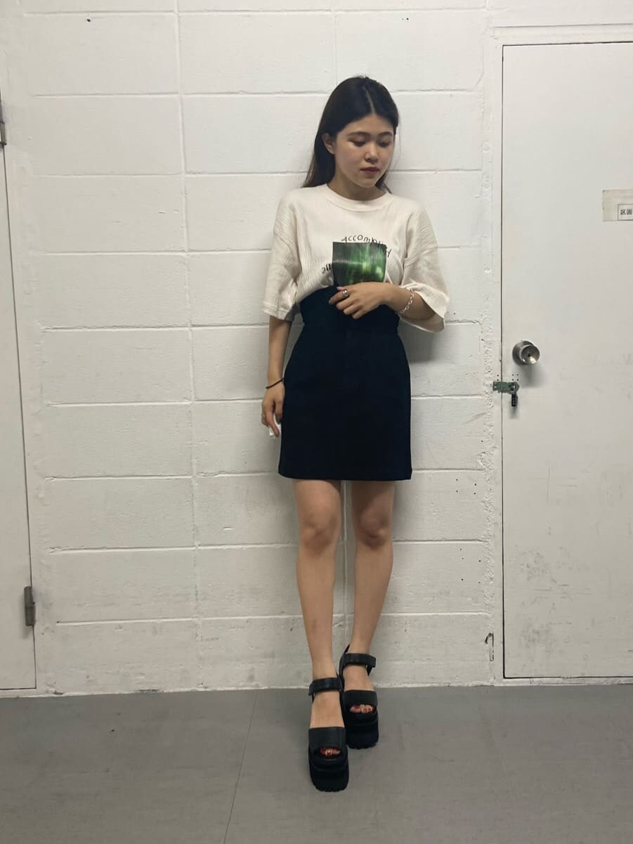 ブラック系のスカート、ブラック系のサンダル、ホワイト系のTシャツ/カットソーを着用したレディースの夏コーディネートの2枚目の写真