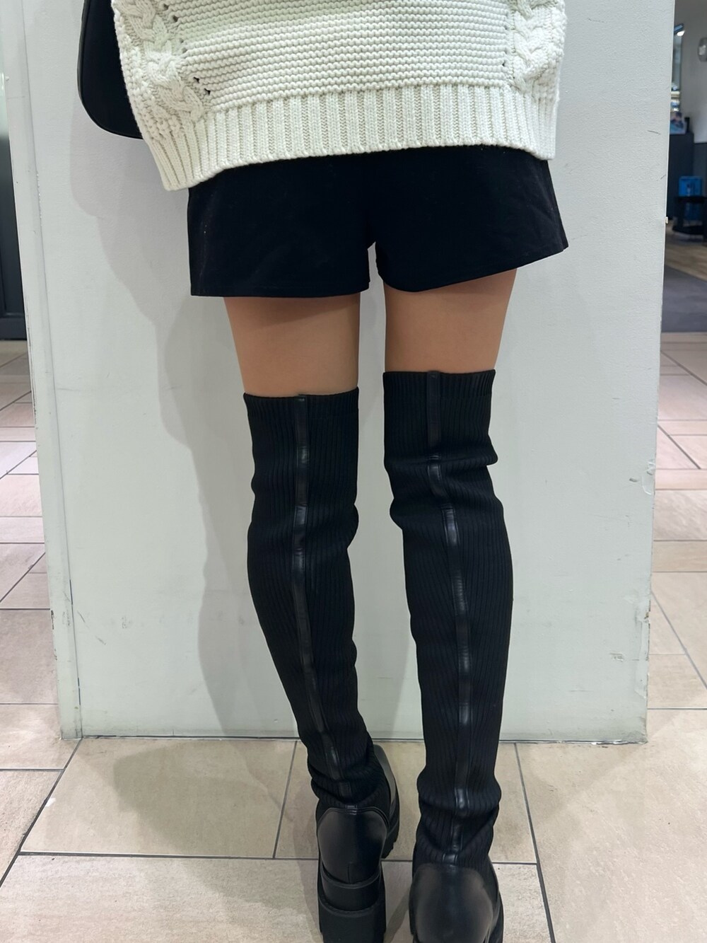 ホワイト系のニット/セーター、ブラック系のその他パンツ、ブラック系のブーツを着用したレディースの秋コーディネートの7枚目の写真