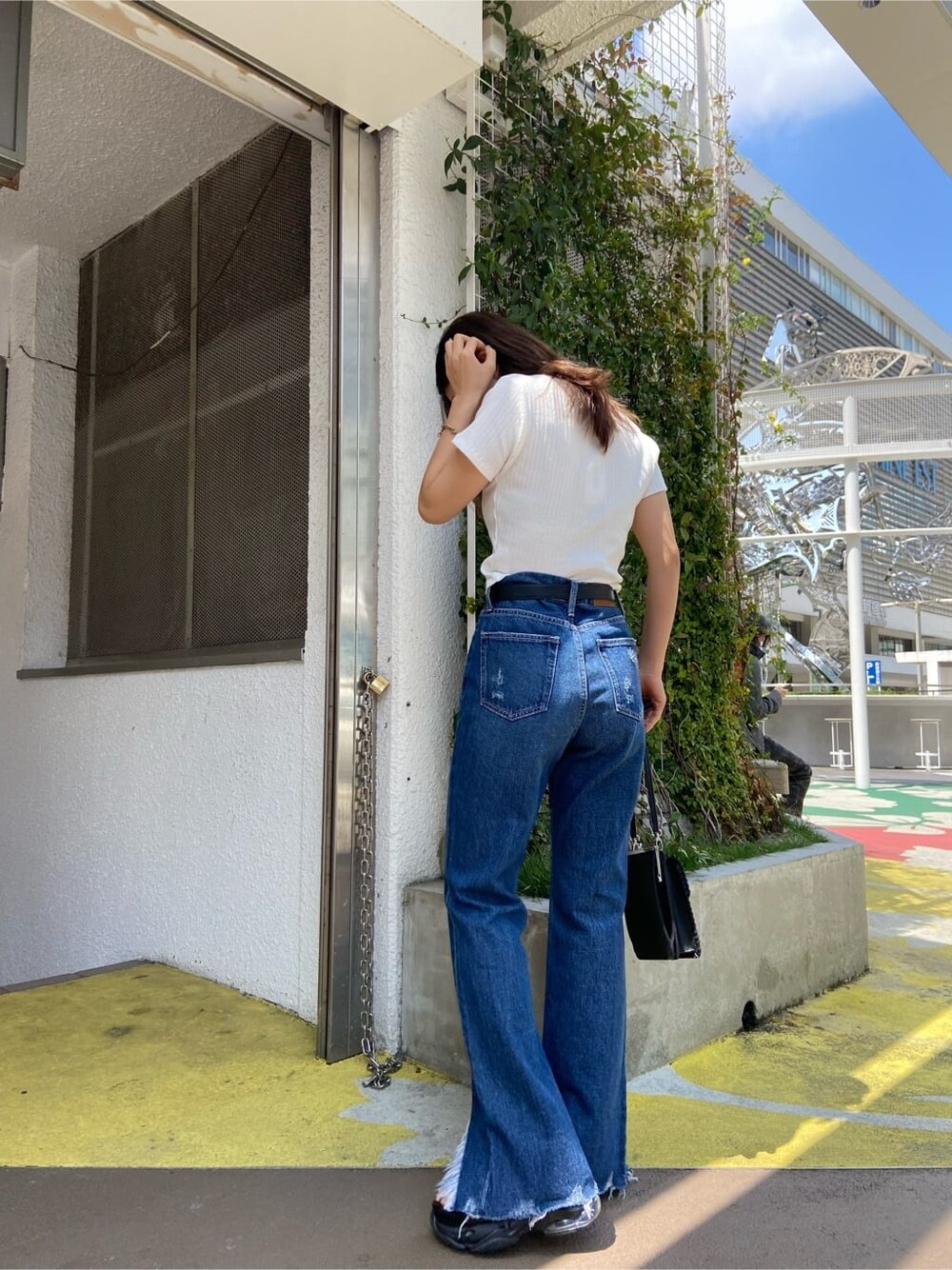 ブラック系のショルダーバッグ、ホワイト系のTシャツ/カットソー、ブルー系のデニムパンツを着用したレディースの春コーディネートの2枚目の写真