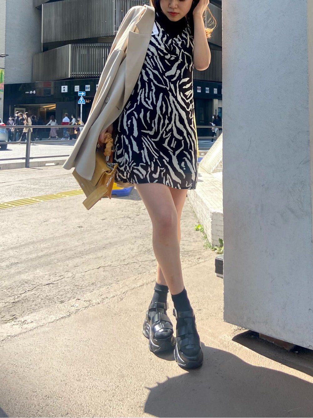 ベージュ系のテーラードジャケット、ブラック系のワンピース、ブラック系のサンダルを着用したレディースの春コーディネートの2枚目の写真