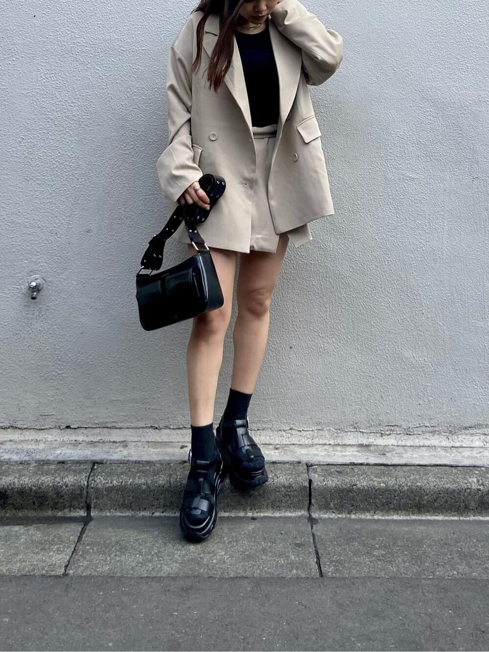 ブラック系のショルダーバッグ、ブラック系のTシャツ/カットソー、ベージュ系のスカートを着用したレディースの春コーディネートの7枚目の写真