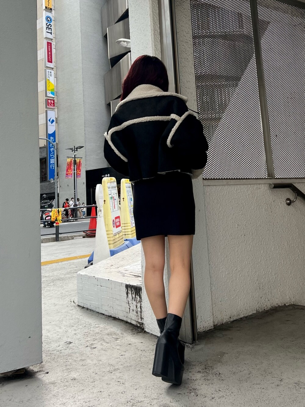 ブラック系のブーツ、ブラック系のムートンコート、ブラック系のワンピースを着用したレディースの秋コーディネートの3枚目の写真