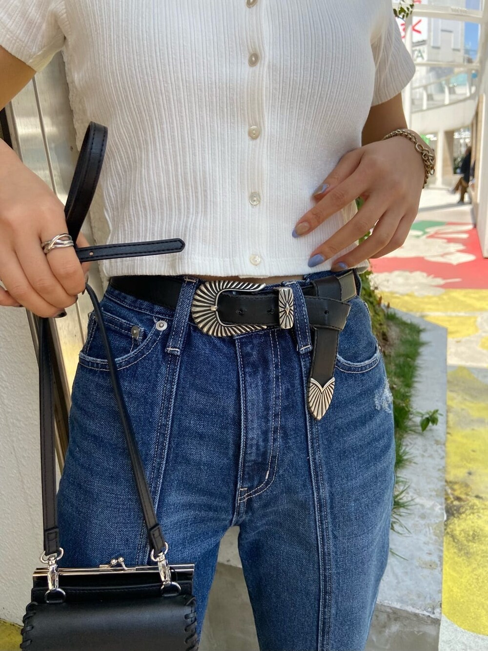 ブラック系のショルダーバッグ、ホワイト系のTシャツ/カットソー、ブルー系のデニムパンツを着用したレディースの春コーディネートの6枚目の写真