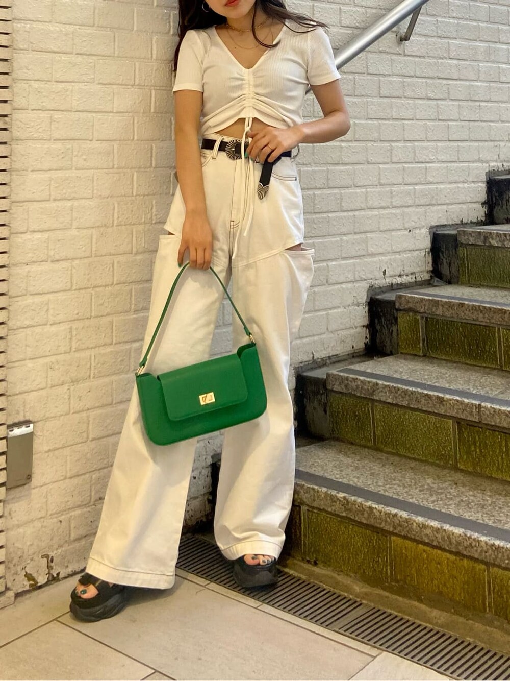 ホワイト系のデニムパンツ、ブラック系のサンダル、グリーン系のショルダーバッグを着用したレディースの春コーディネートの2枚目の写真