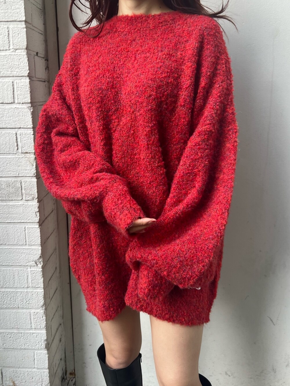 レッド系のニット/セーター、ブラック系のブーツを着用したレディースの冬コーディネートの5枚目の写真