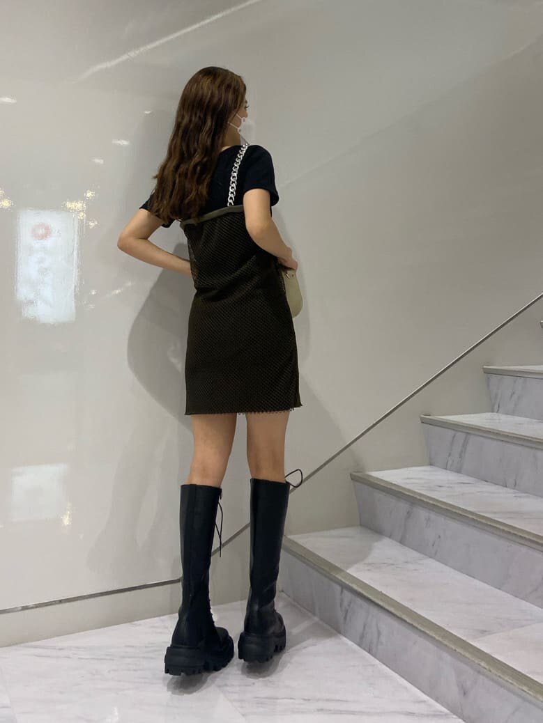 ブラック系のブーツ、ホワイト系のショルダーバッグ、ブラック系のワンピースを着用したレディースの夏コーディネートの4枚目の写真