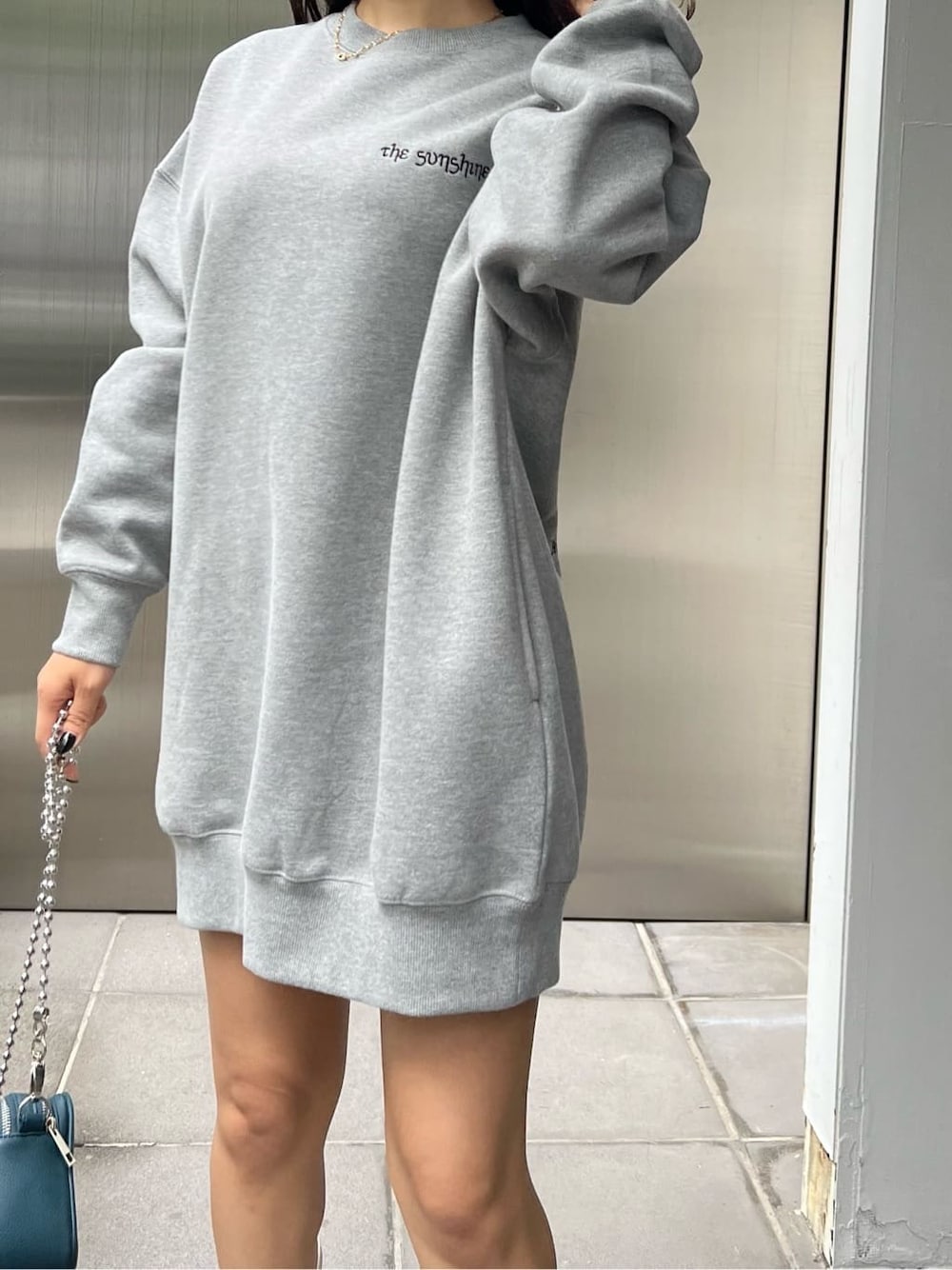 グリーン系のショルダーバッグ、グレー系のスウェット、ホワイト系のブーツを着用したレディースの秋コーディネートの5枚目の写真