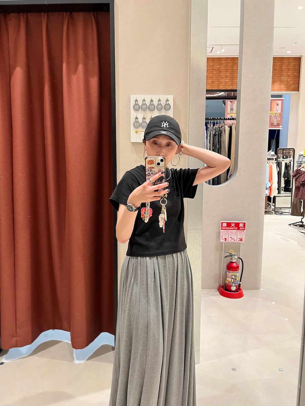 ブラック系のTシャツ/カットソー、グレー系のスカート、ブラック系のキャップを着用したレディースの夏コーディネートの2枚目の写真