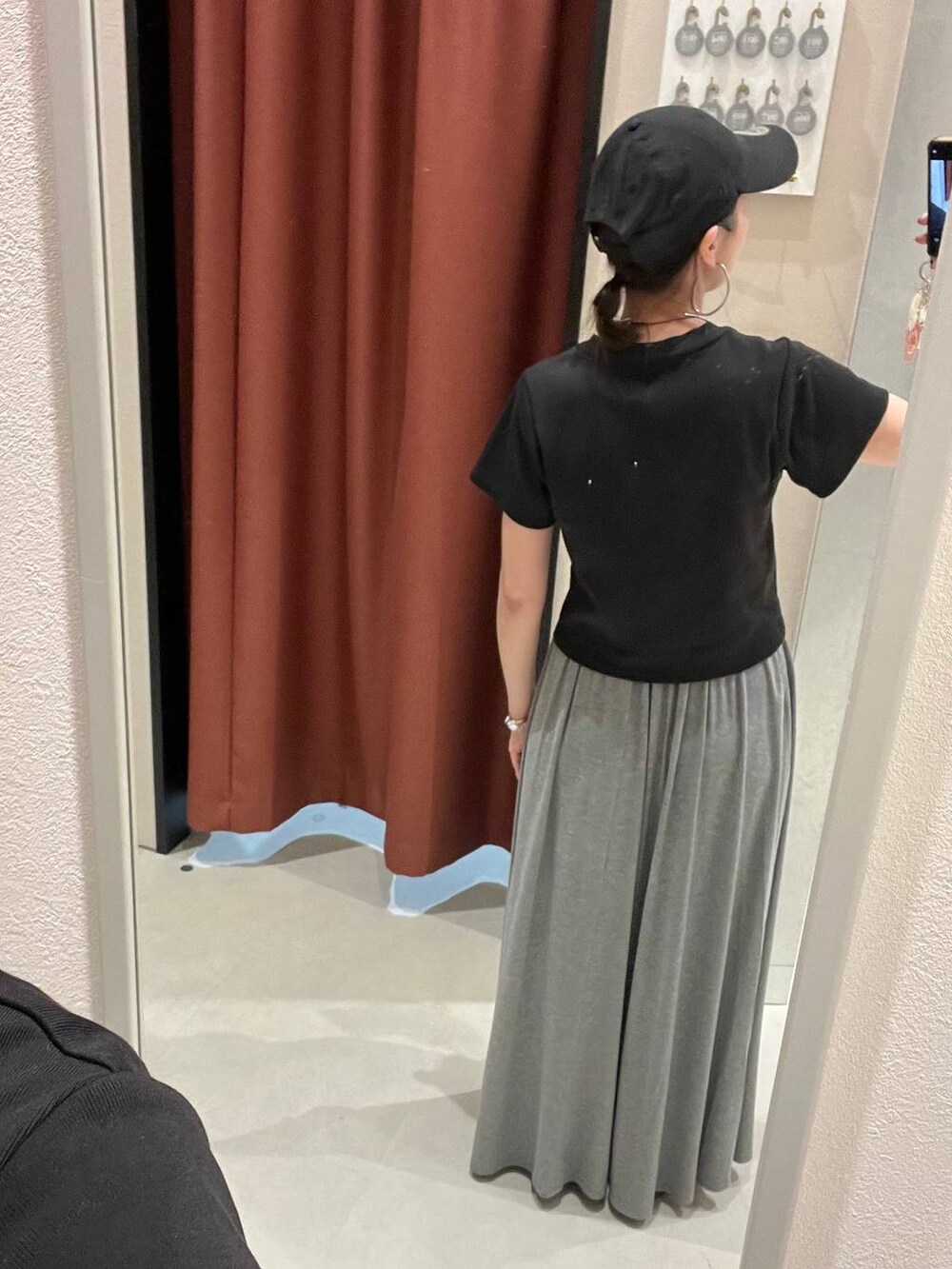 ブラック系のTシャツ/カットソー、グレー系のスカート、ブラック系のキャップを着用したレディースの夏コーディネートの3枚目の写真