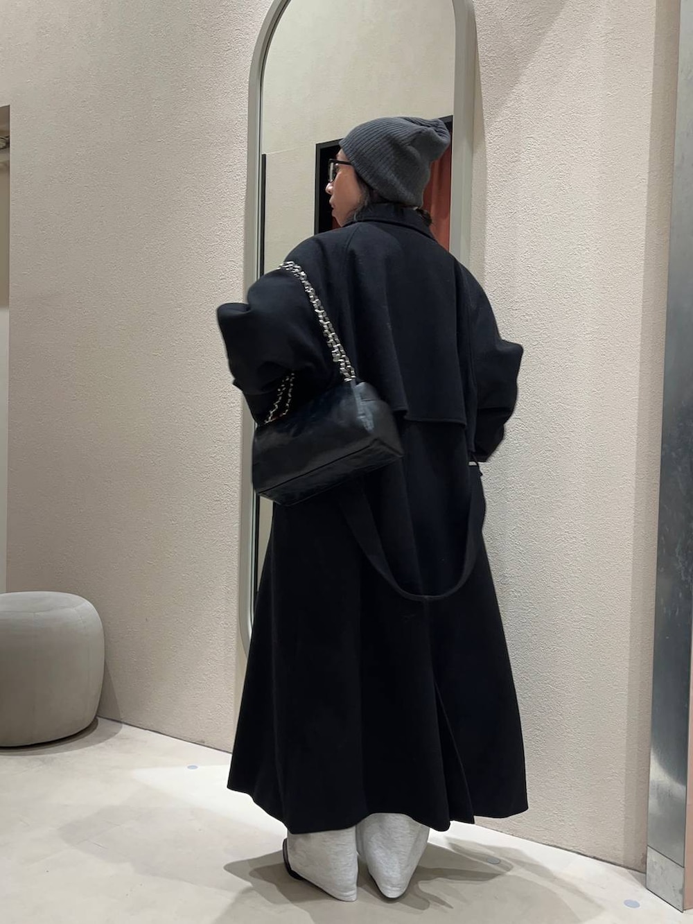 ブラック系のステンカラーコート、グレー系のスウェットパンツ、グレー系のニット/セーターを着用したレディースの冬コーディネートの2枚目の写真