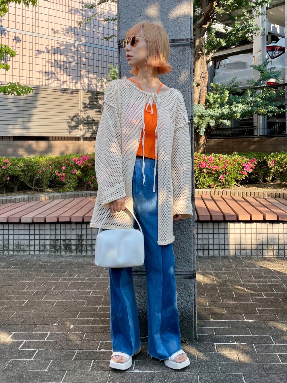 ベージュ系のTシャツ/カットソー、オレンジ系のキャミソール、ブルー系のデニムパンツを着用したレディースの春コーディネートの2枚目の写真