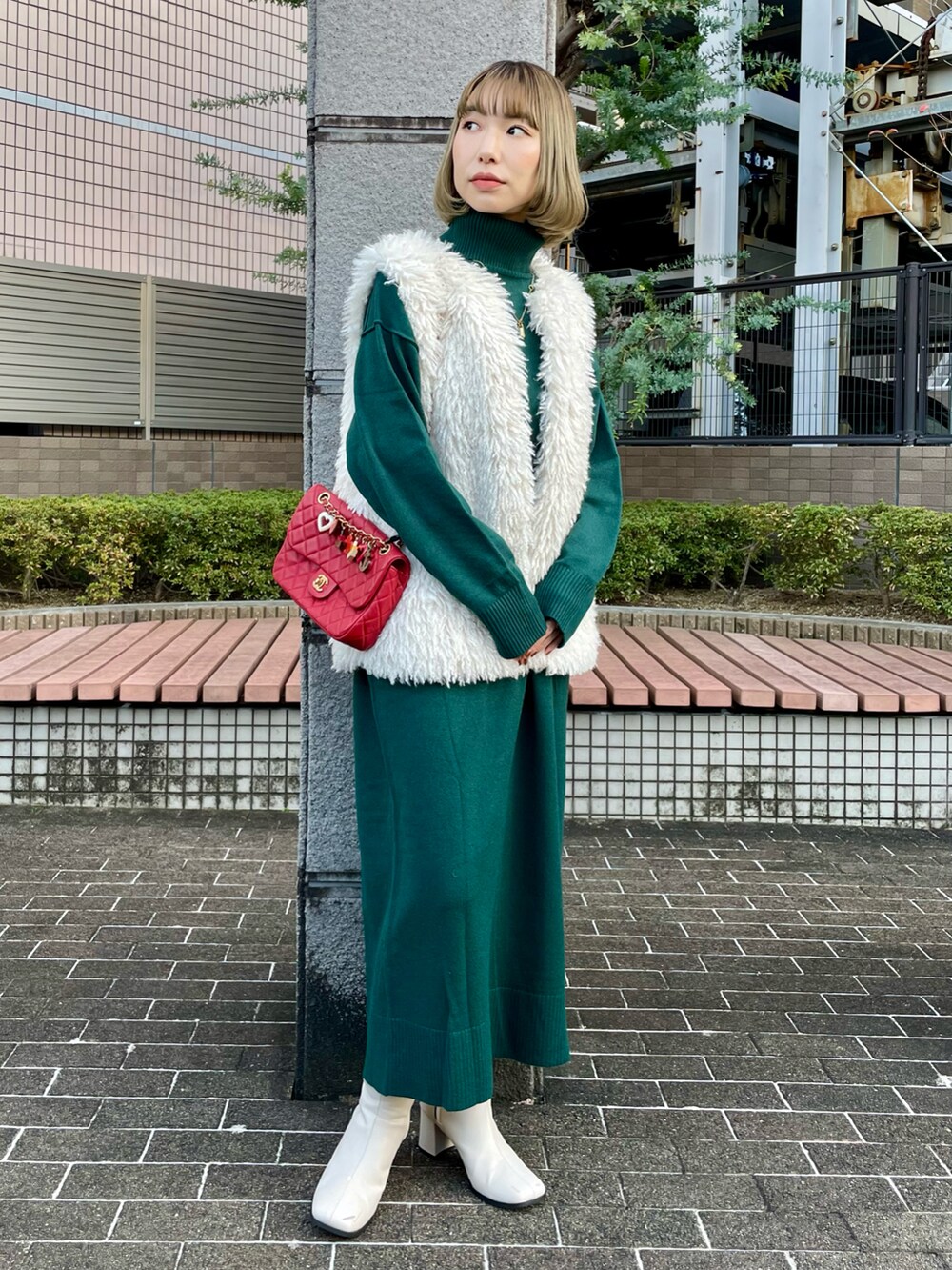 ホワイト系のベスト、グリーン系のワンピース、ホワイト系のブーツを着用したレディースの冬コーディネートの2枚目の写真