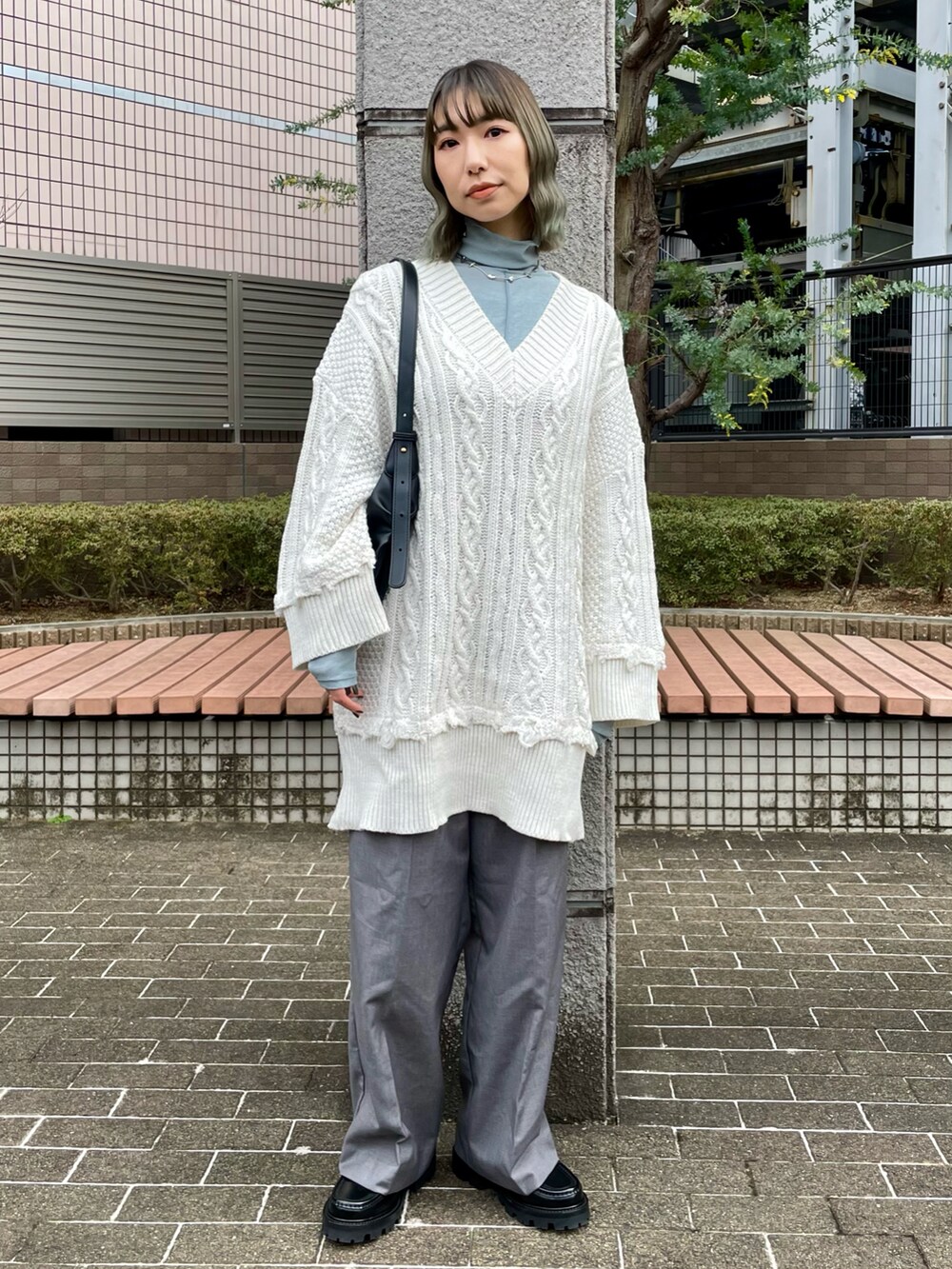 ホワイト系のニット/セーター、ブルー系のTシャツ/カットソー、グレー系のスラックスを着用したレディースの冬コーディネートの2枚目の写真