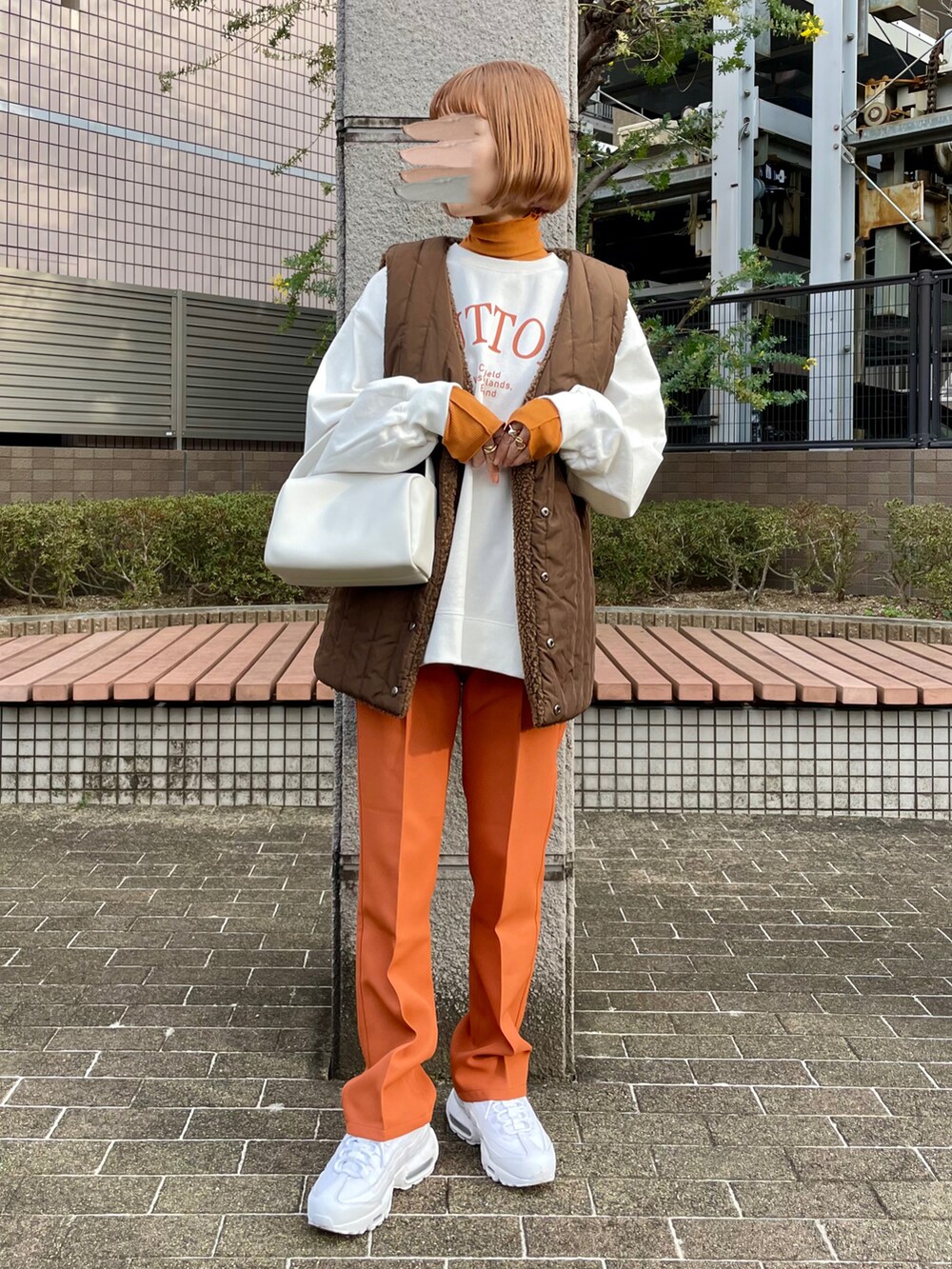 ホワイト系のスウェット、ホワイト系のハンドバッグ、オレンジ系のスラックスを着用したレディースの春コーディネートの2枚目の写真