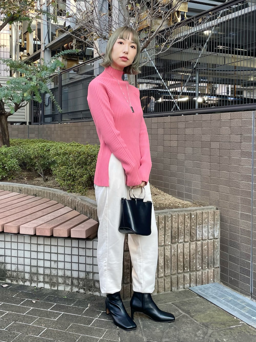 ブラウン系のステンカラーコート、ピンク系のニット/セーター、ホワイト系のスウェットパンツを着用したレディースの秋コーディネートの3枚目の写真
