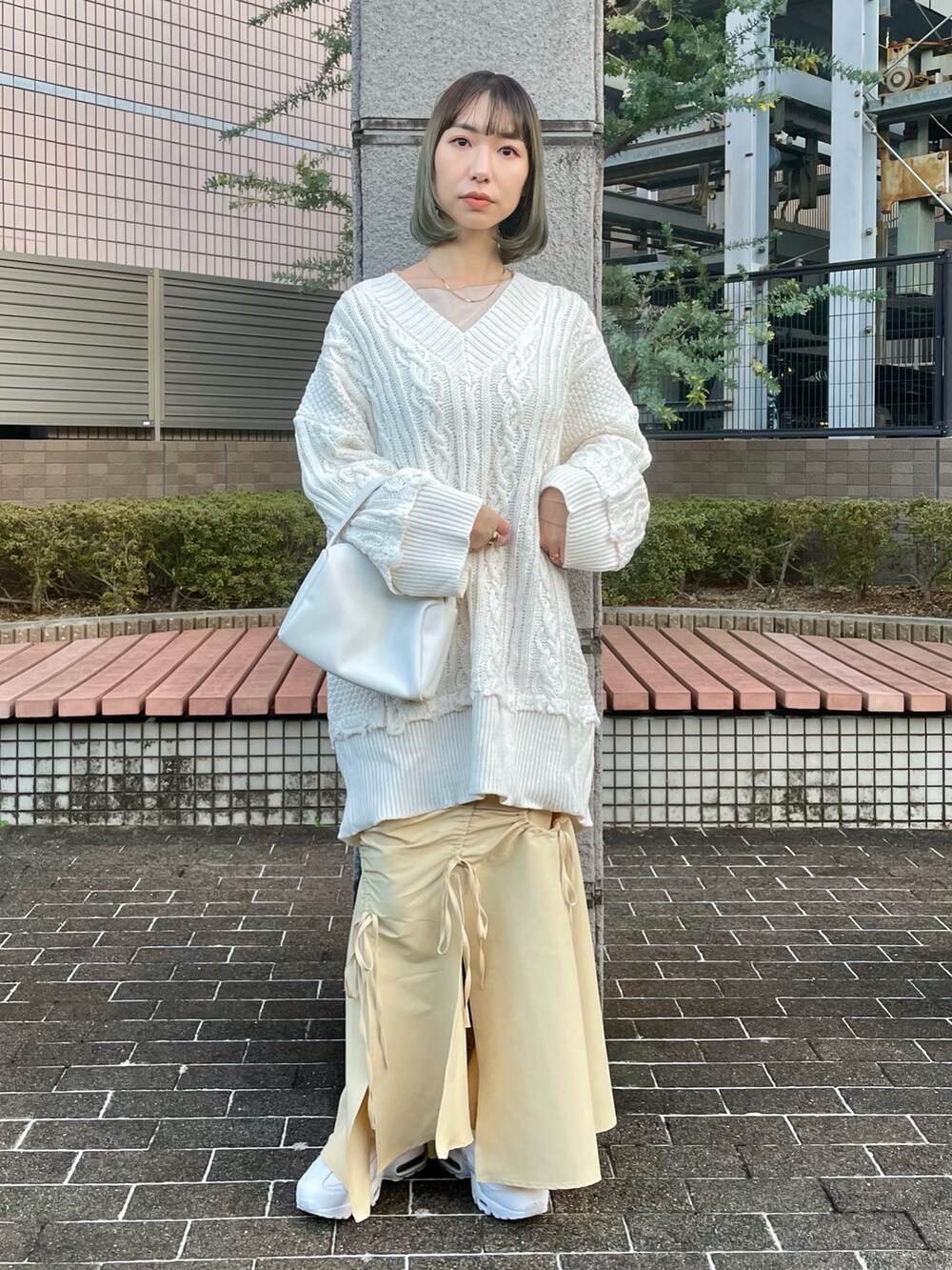 ホワイト系のニット/セーター、イエロー系のTシャツ/カットソー、イエロー系のスカートを着用したレディースの冬コーディネートの2枚目の写真