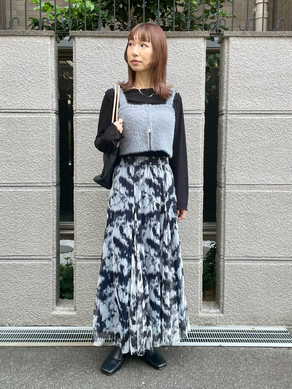 ブルー系のスカート、グレー系のベスト、ブラック系のTシャツ/カットソーを着用したレディースの秋コーディネートの2枚目の写真