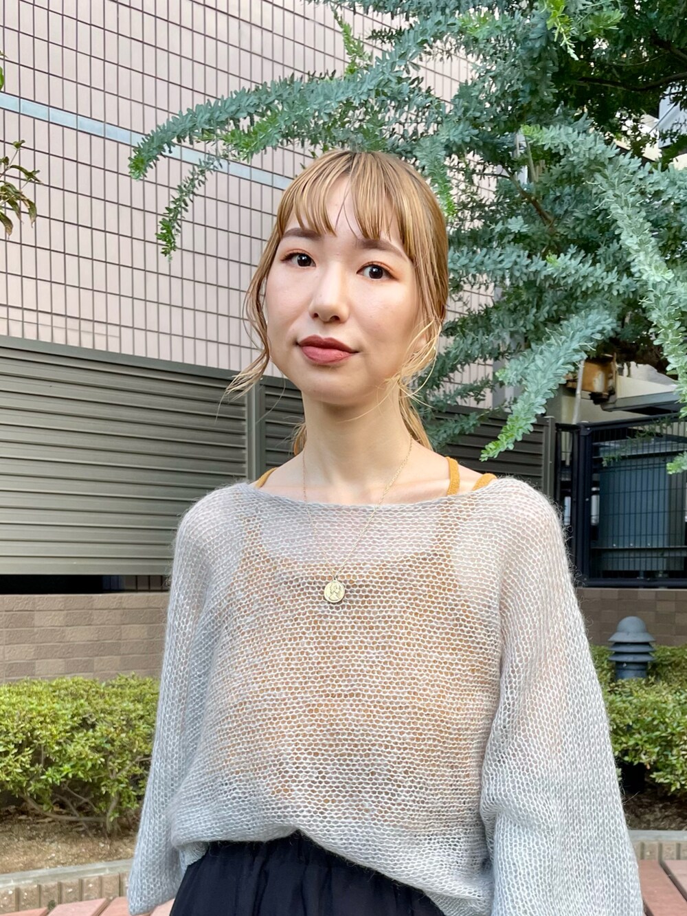 グレー系のニット/セーター、ブラック系のスカート、オレンジ系のキャミソールを着用したレディースの夏コーディネートの3枚目の写真