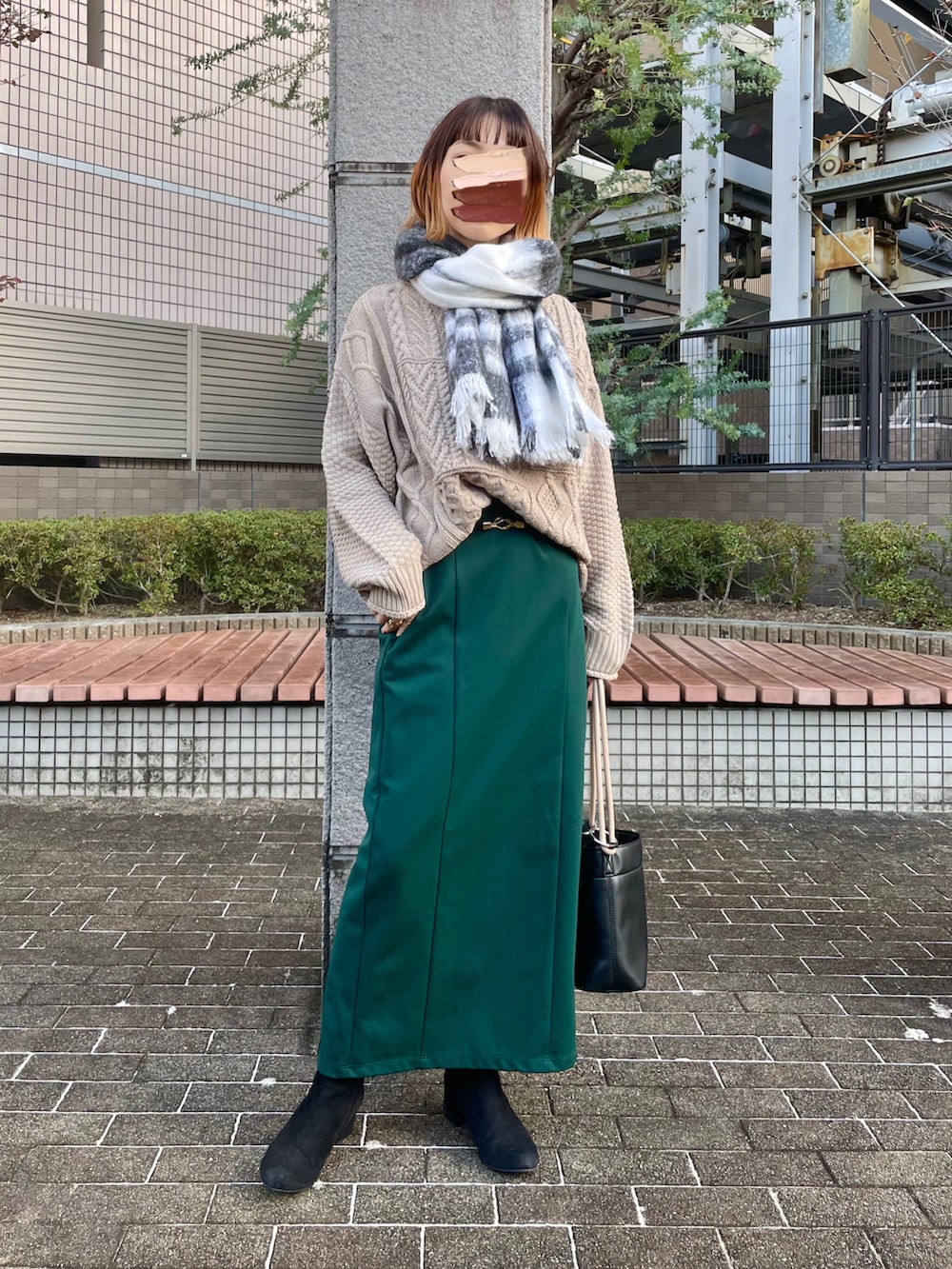 ベージュ系のチェスターコート、グリーン系のスカート、ベージュ系のニット/セーターを着用したレディースの秋コーディネートの2枚目の写真