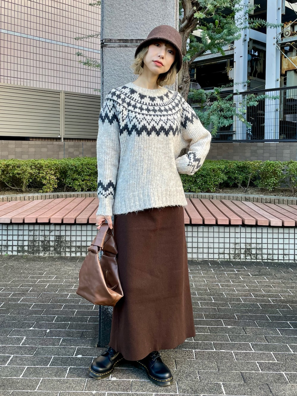 ホワイト系のニット/セーター、ブラウン系のスカート、ベージュ系のチェスターコートを着用したレディースの冬コーディネートの2枚目の写真