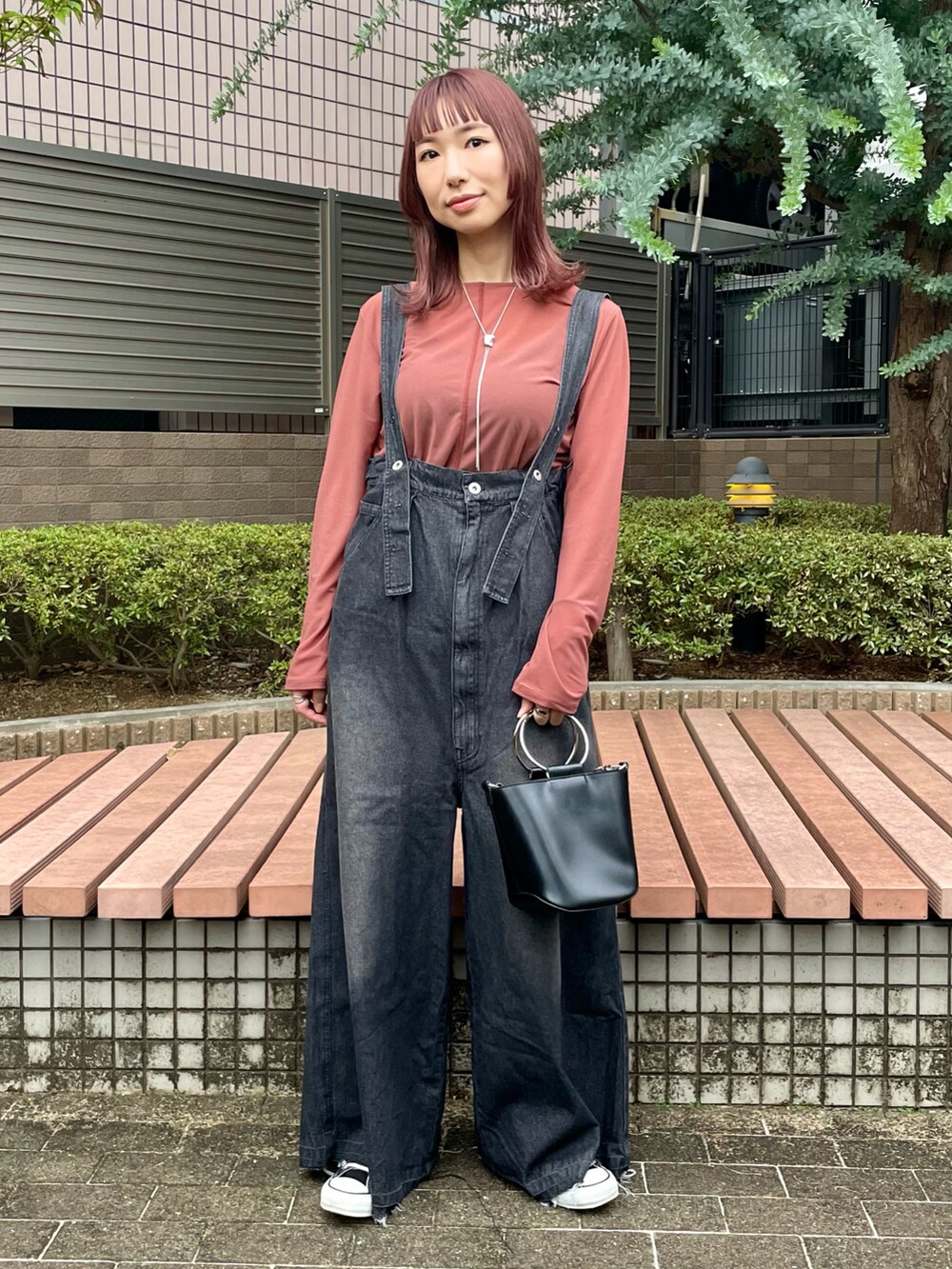 ブラック系のサロペット/オーバーオール、ピンク系のTシャツ/カットソー、ホワイト系のベストを着用したレディースの秋コーディネートの2枚目の写真