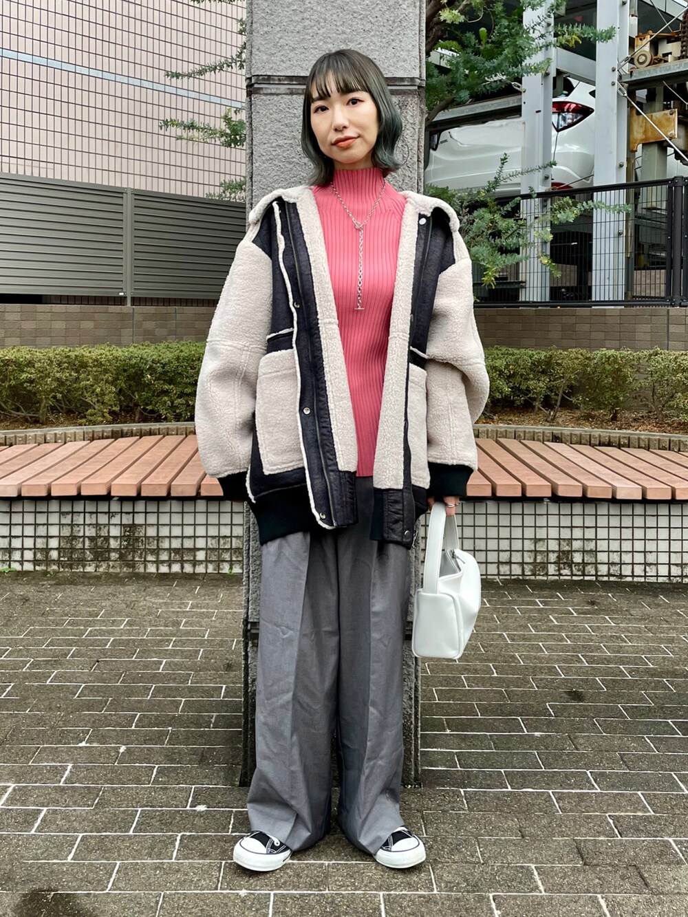 ブラック系のムートンコート、ピンク系のニット/セーター、グレー系のスラックスを着用したレディースの冬コーディネートの2枚目の写真