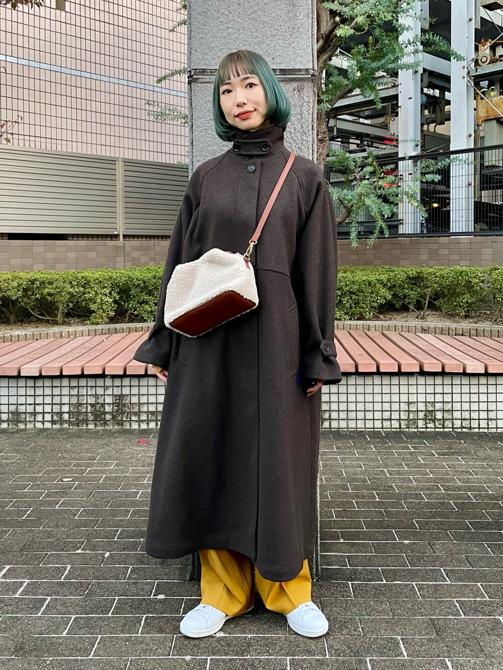 ブラウン系のステンカラーコート、イエロー系のスラックス、ホワイト系のニット/セーターを着用したレディースの秋コーディネートの2枚目の写真