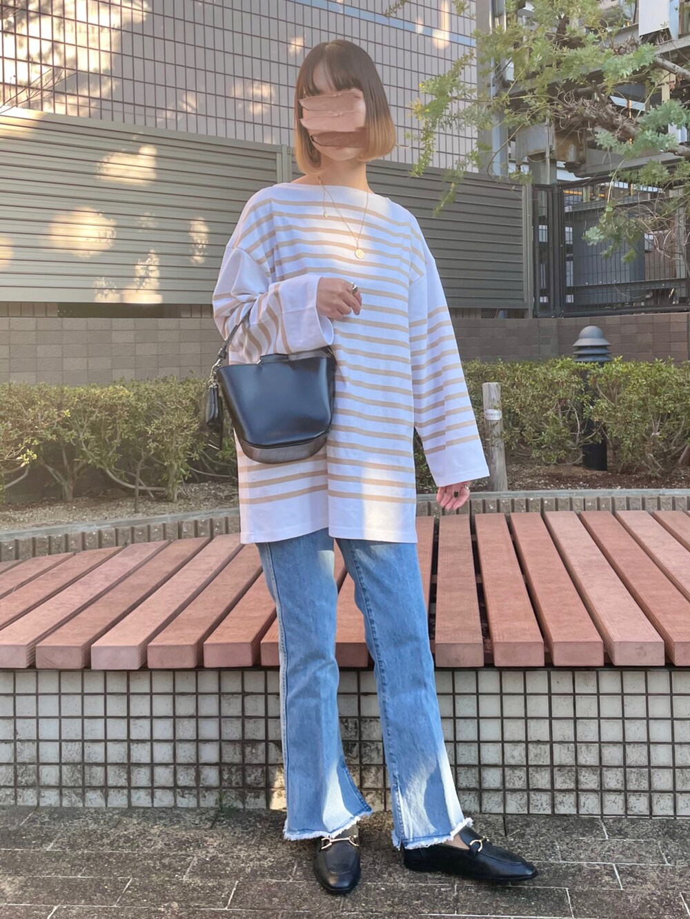 グリーン系のトレンチコート、ブラック系のショルダーバッグ、ブラック系のローファーを着用したレディースの冬コーディネートの2枚目の写真