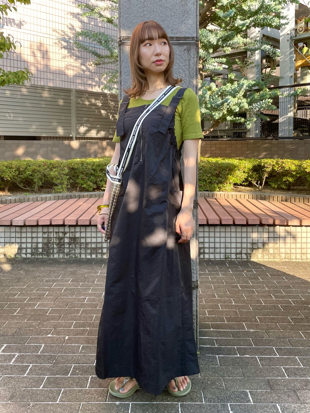 ブラック系のジャンパースカート、グリーン系のTシャツ/カットソー、グリーン系のサンダルを着用したレディースの夏コーディネートの2枚目の写真