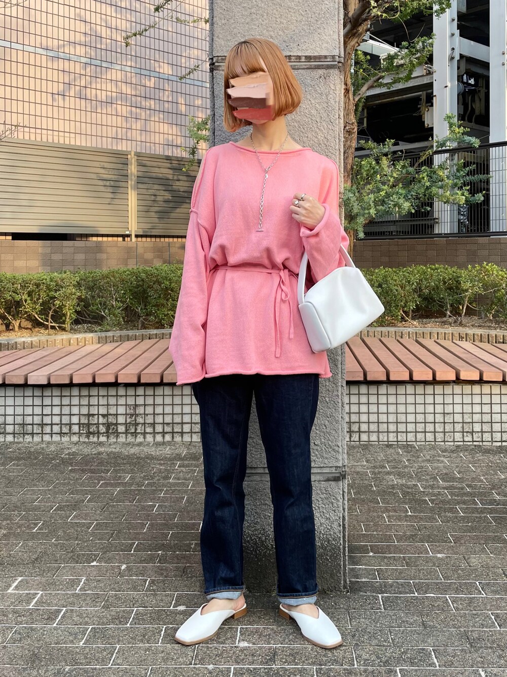 ピンク系のニット/セーター、ブルー系のデニムパンツ、ホワイト系のハンドバッグを着用したレディースの春コーディネートの2枚目の写真