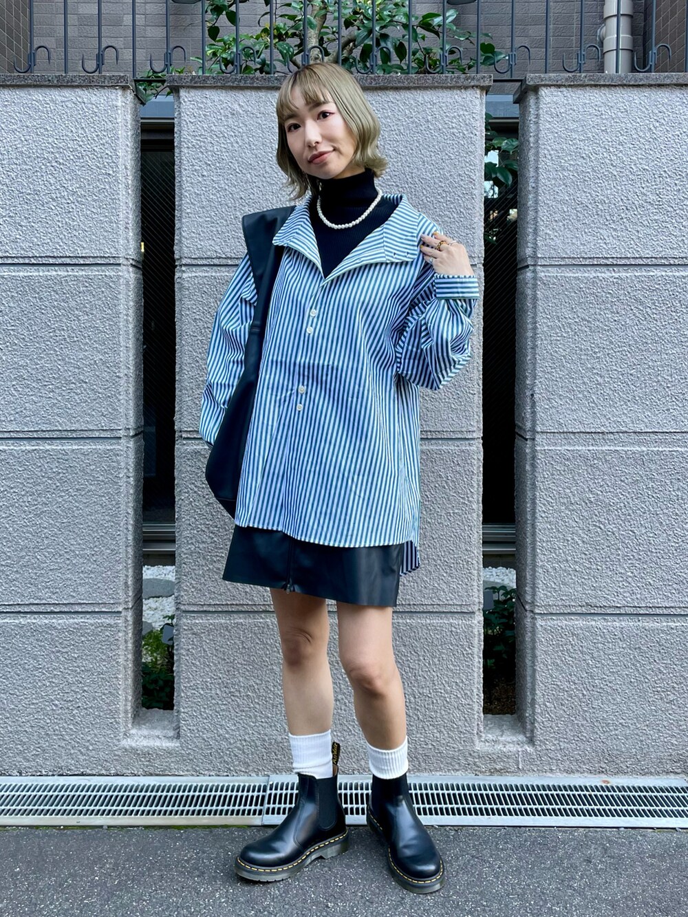 グリーン系のシャツ/ブラウス、ブラック系のニット/セーター、ブラック系のスカートを着用したレディースの秋コーディネートの2枚目の写真