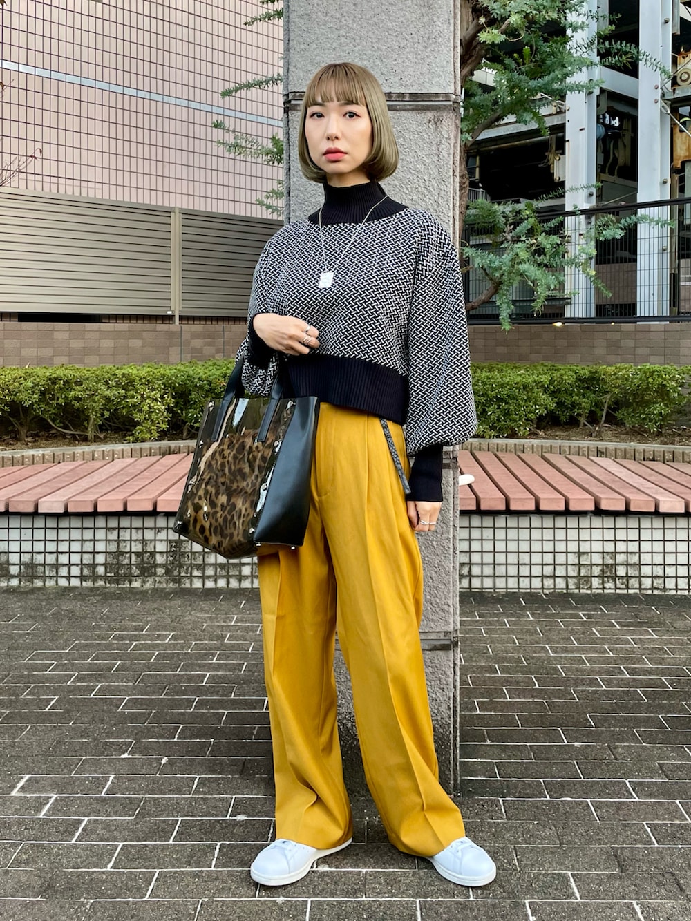 ホワイト系のナイロンジャケット、イエロー系のスラックス、ブラック系のニット/セーターを着用したレディースの冬コーディネートの2枚目の写真